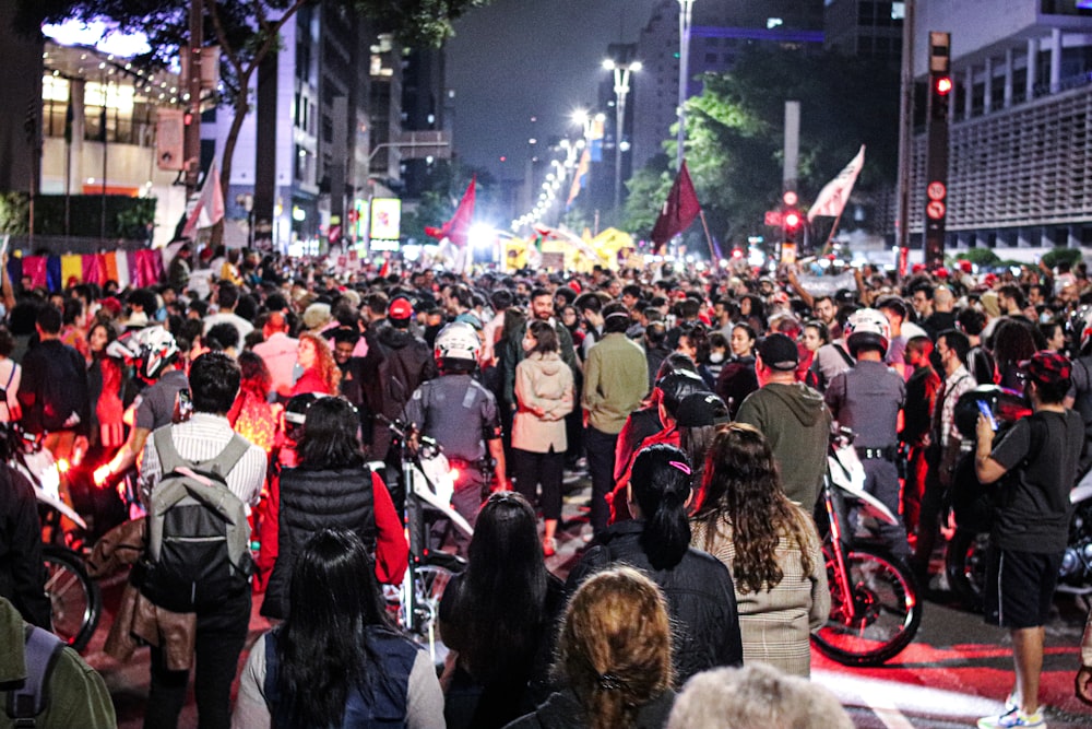 a large group of people walking down a street at night