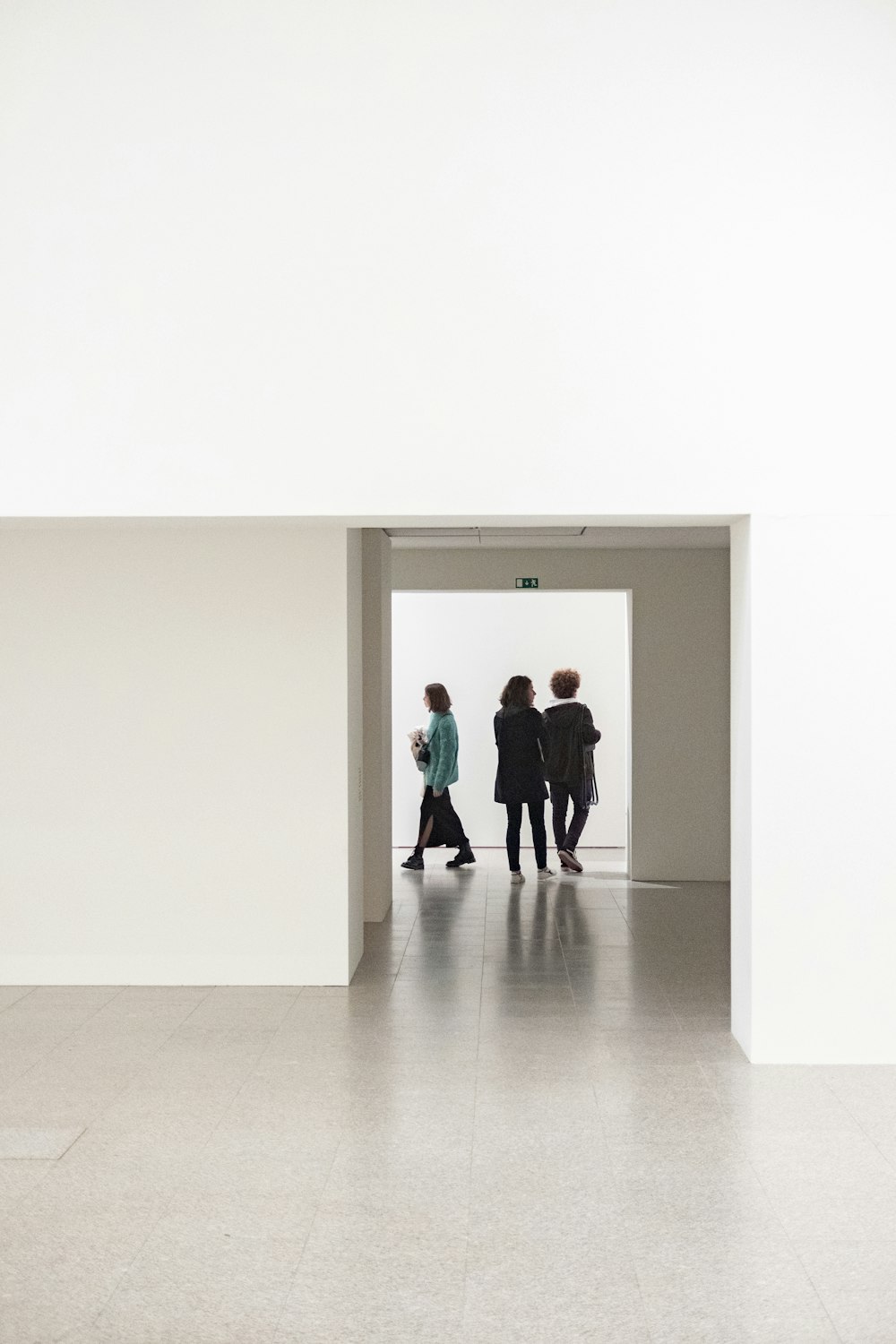 a group of people walking through a white room