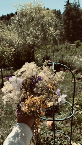 A warm, inviting photo of Florinette gently holding a bouquet of wildflowers in a sunlit garden.