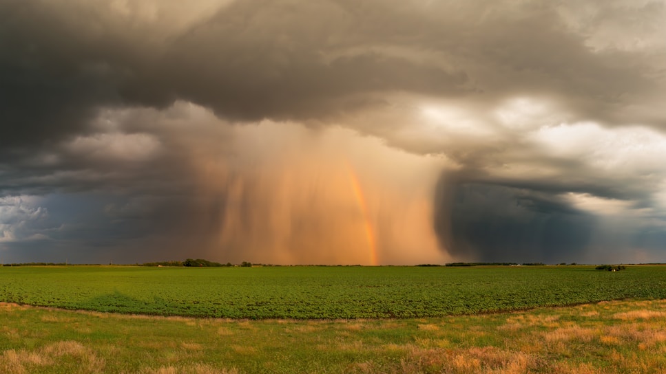 a storm is coming in over a green field