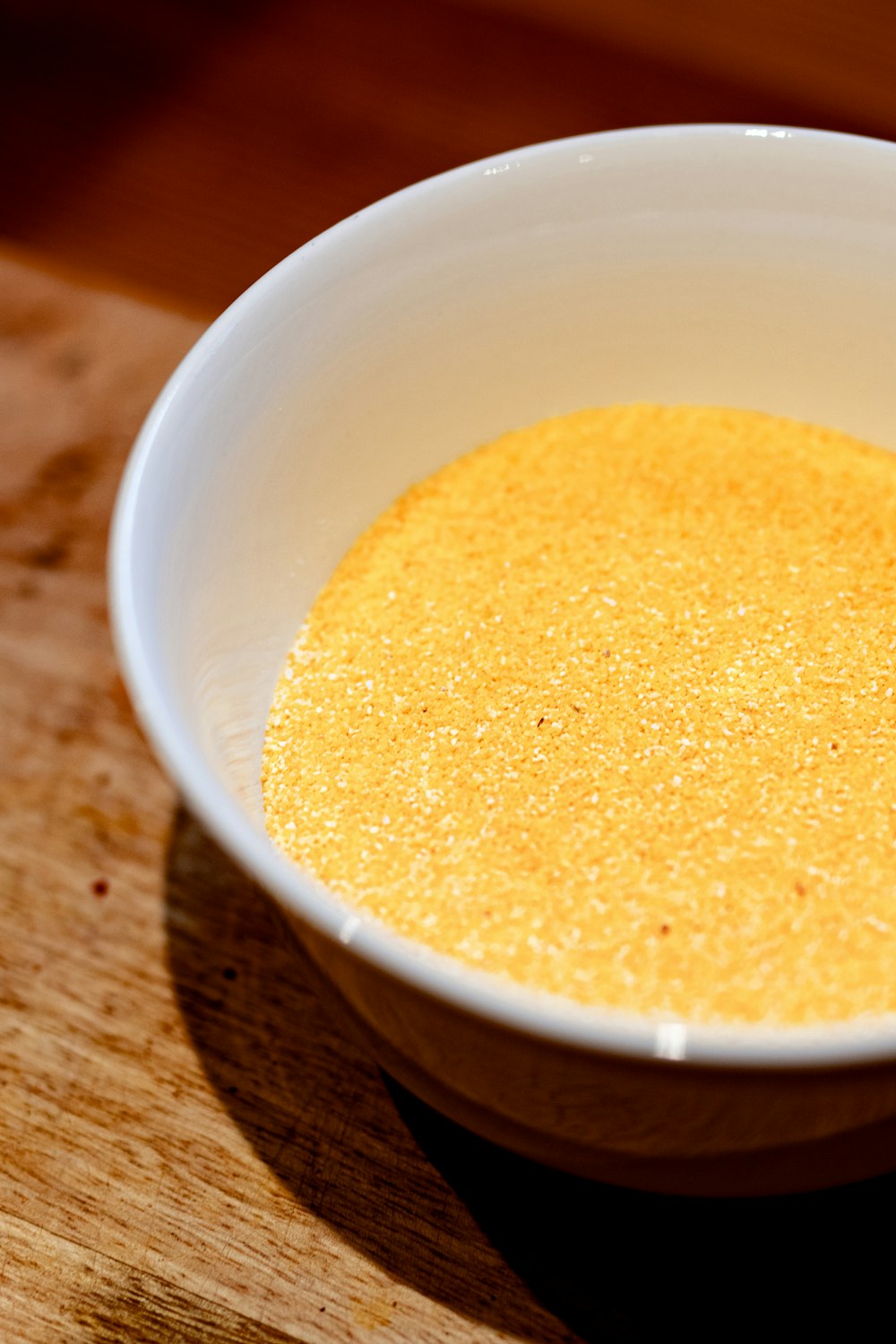 a white bowl filled with yellow liquid on top of a wooden table