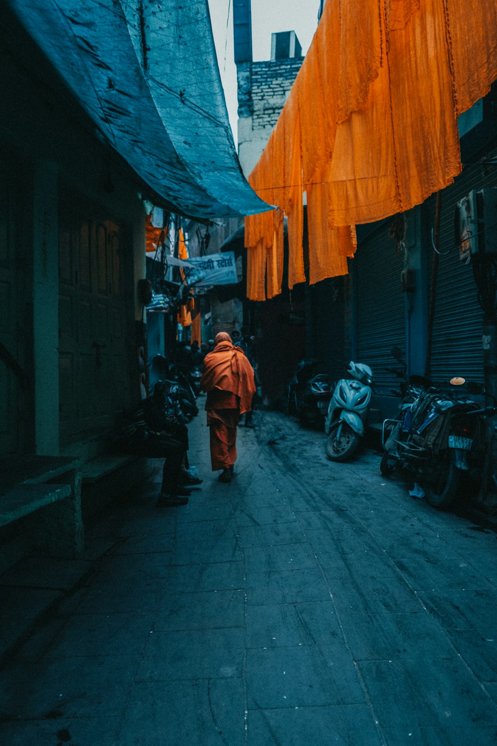a man in an orange outfit walking down a street