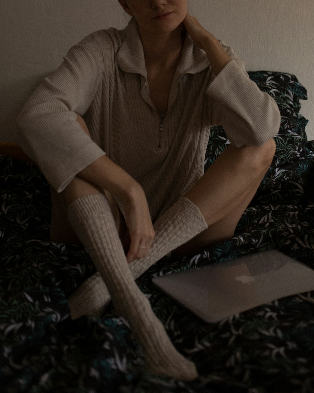 a woman sitting on top of a bed next to a laptop computer