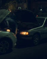 A technician carefully installing a new car battery under the hood of a sleek sedan.