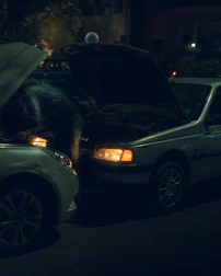 Hands exchanging cash over the hood of a worn-out car in bright daylight.
