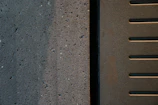 Close-up of textured raw concrete surface juxtaposed with smooth black metal detailing.
