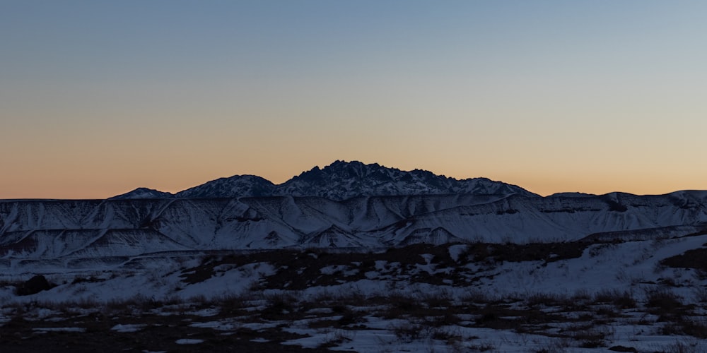 a view of a snowy mountain range at sunset
