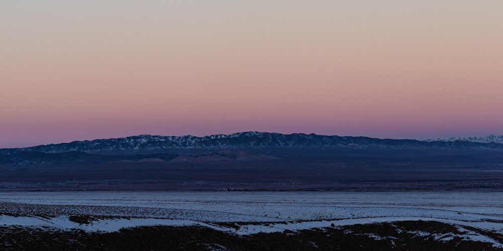a view of a mountain range with a pink sky