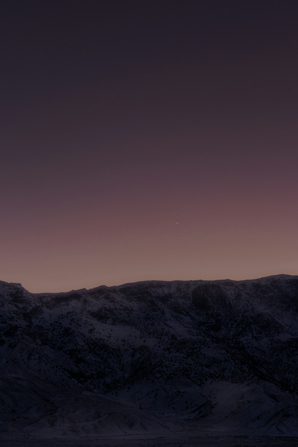 a plane flying in the sky over a mountain range