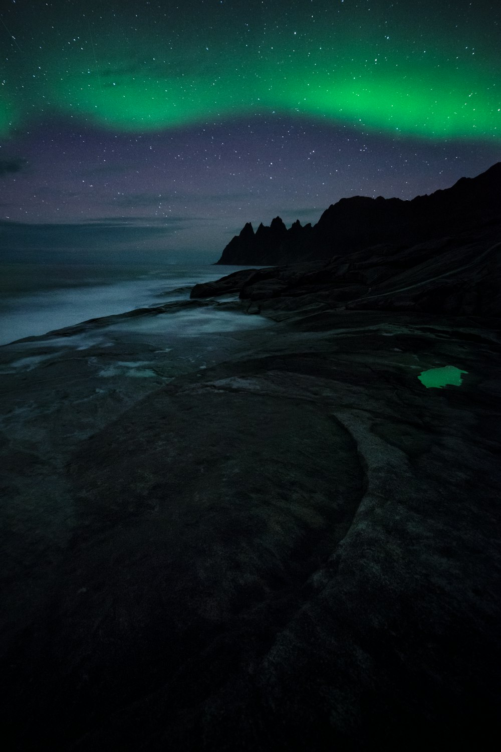 uma aurora verde e preta sobre um corpo de água