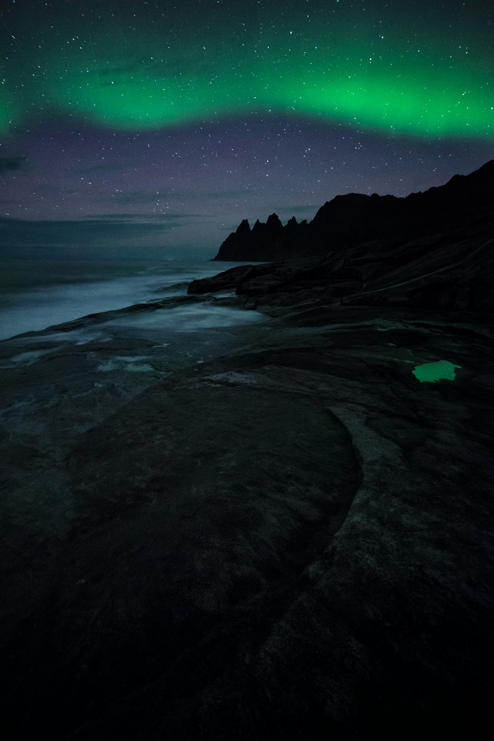 a green and black aurora over a body of water