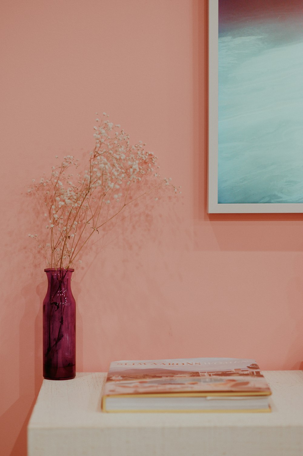 a vase of flowers sitting on a table next to a painting