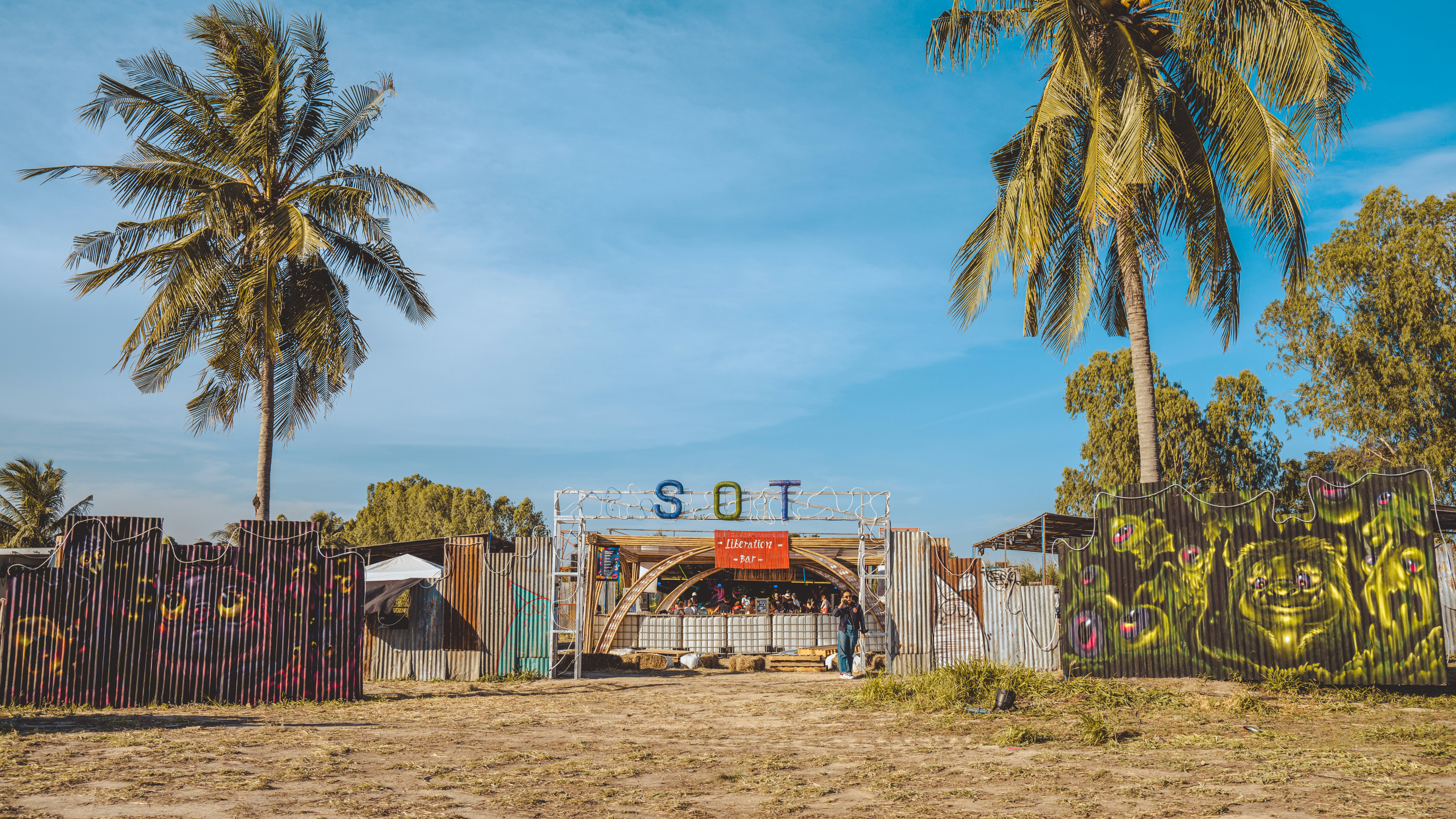 a gate with graffiti on it and palm trees in the background