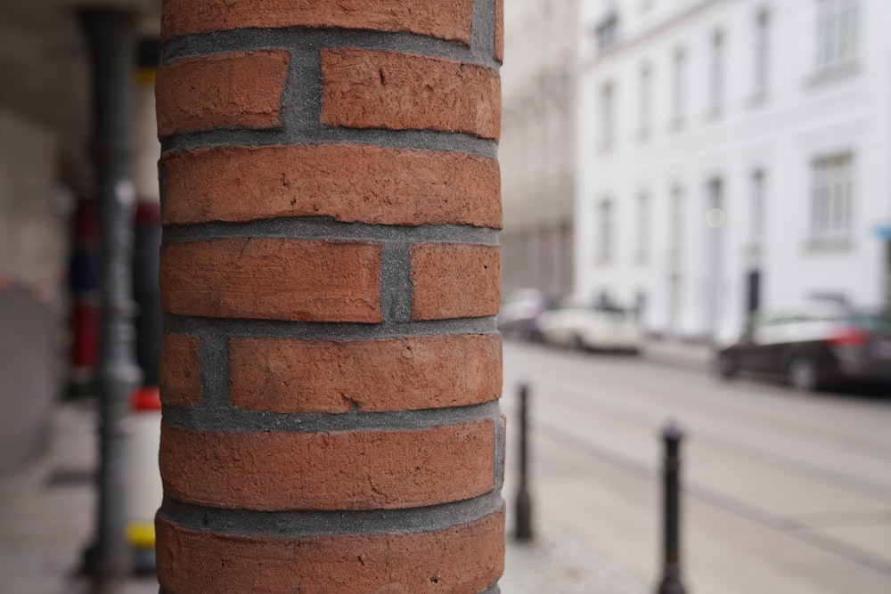 a brick pillar on a city street next to a building
