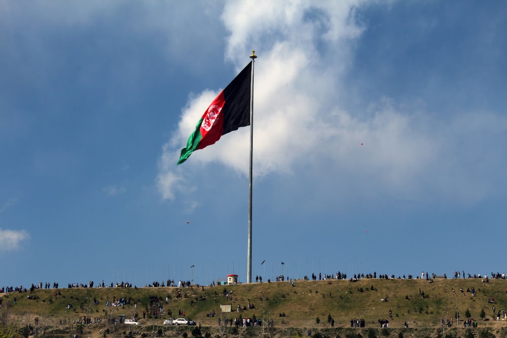 Un drapeau flottant au sommet d’une colline sous un ciel bleu