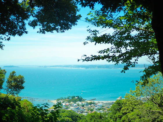 A serene view of Ducos town with lush greenery and nearby coastline under a bright blue sky.