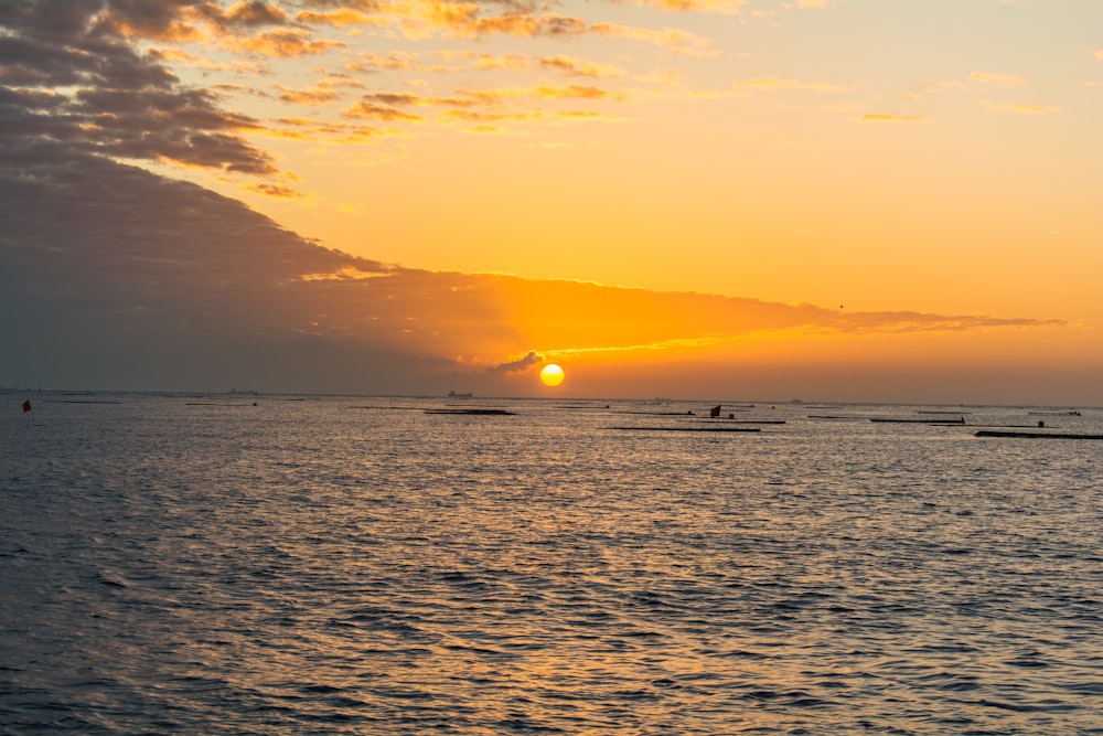 a sunset over the ocean with boats in the water