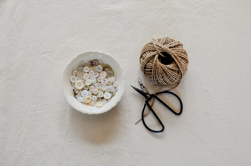 a bowl of buttons next to a pair of scissors