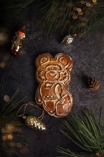 A close-up of a handmade butterscotch bear figurine with delicate painted details and a tiny scarf.
