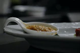 Close-up photo of a baby tasting a spoonful of pureed food, with a curious expression.
