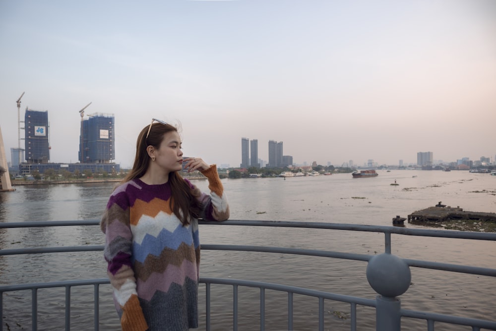 a woman standing on a bridge next to a body of water