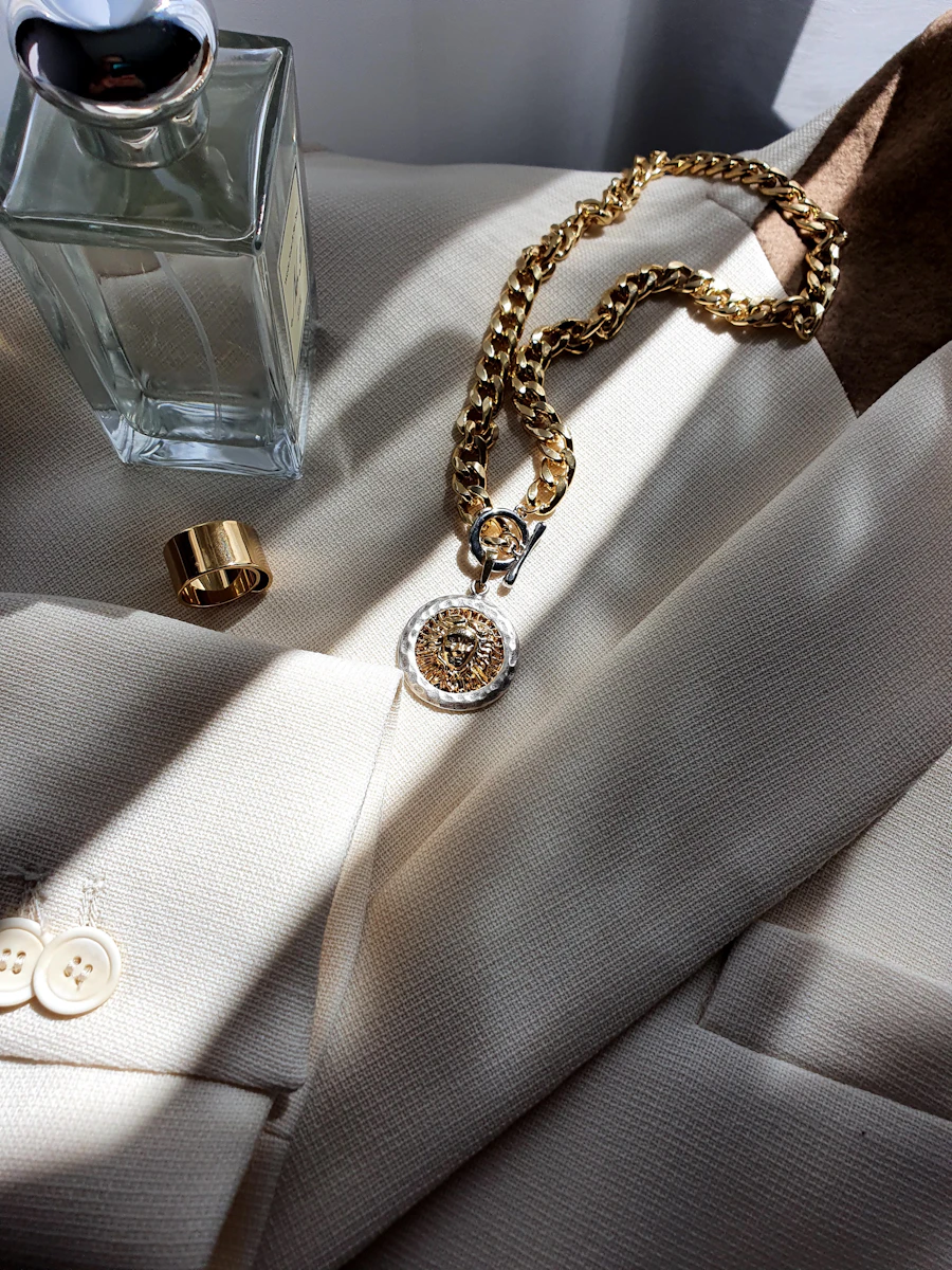 Perfume, jewelry and cream blazer in sunlight