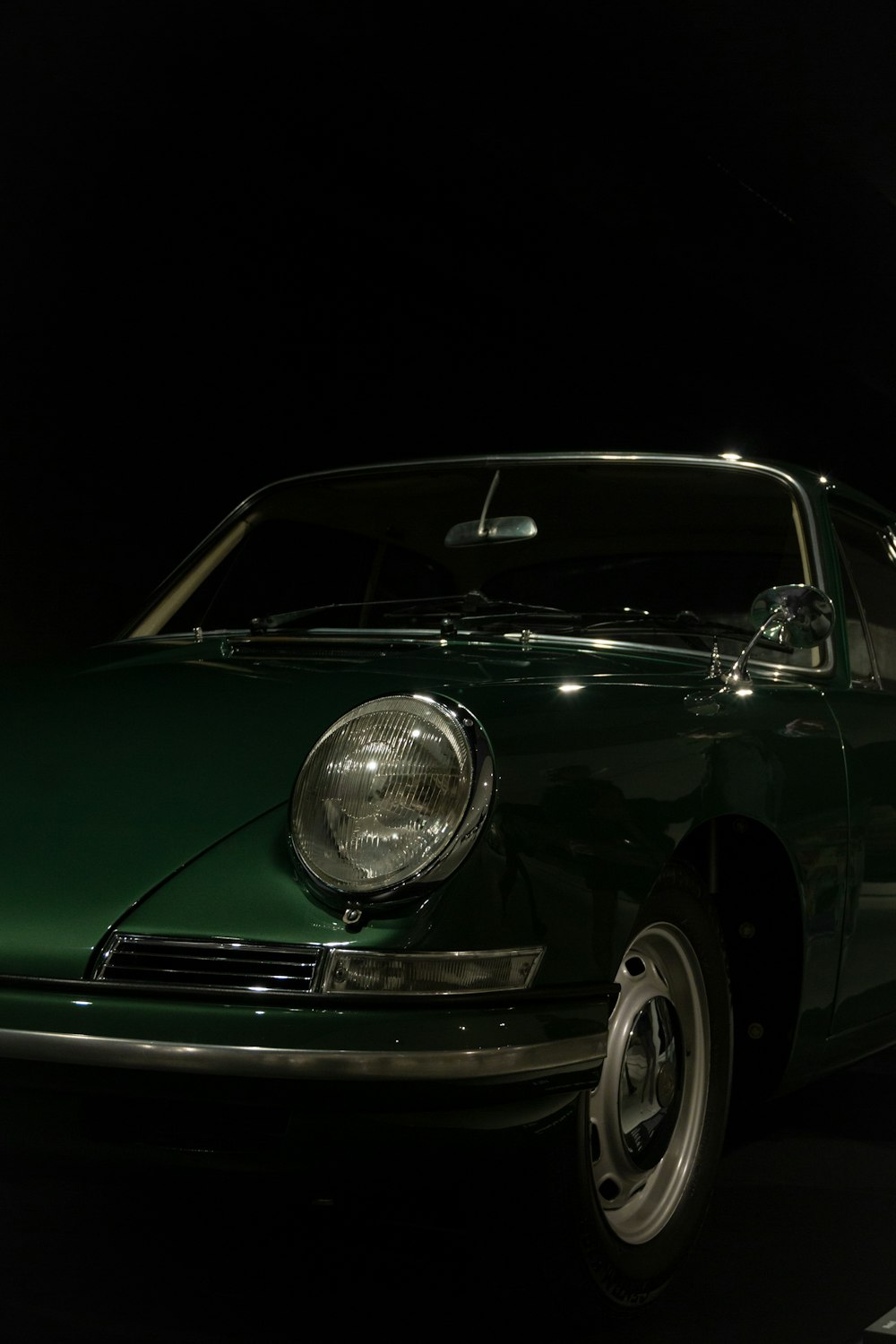 a green car parked in a dark room