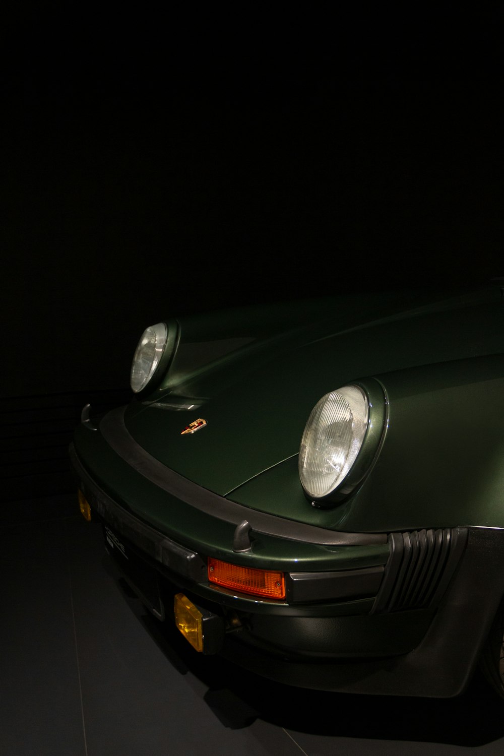 Un coche deportivo verde estacionado en una habitación oscura