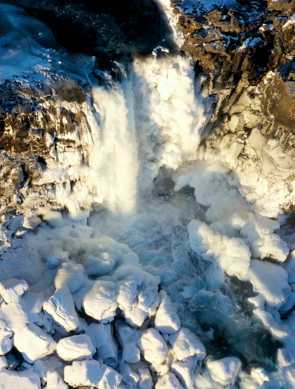 an aerial view of a waterfall in the snow