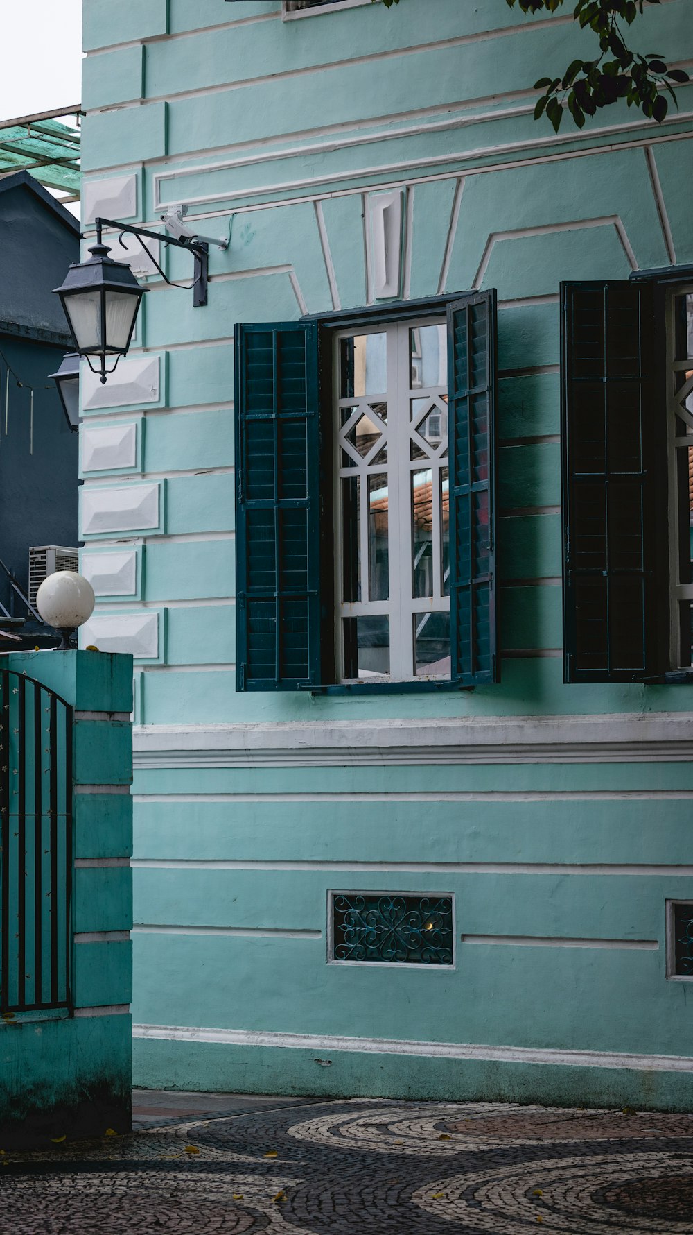 a blue building with green shutters and a clock