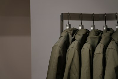 Des vestes olive à capuche suspendues à une barre
