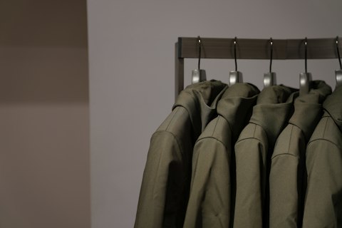 Des vestes olive suspendues à une barre