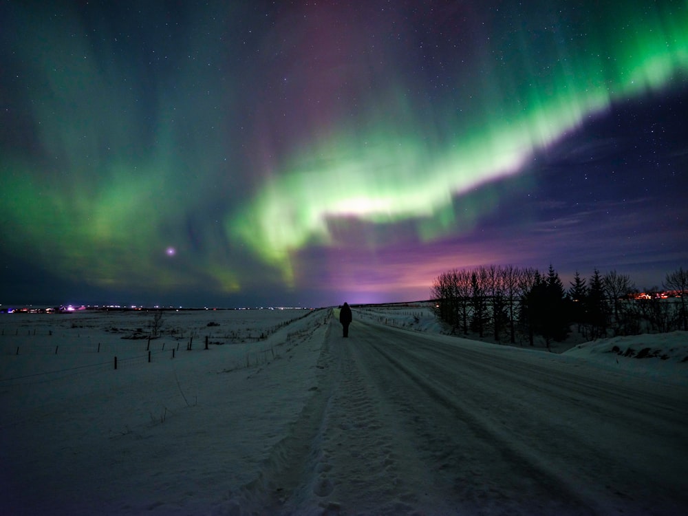 a person standing in the middle of a snow covered road