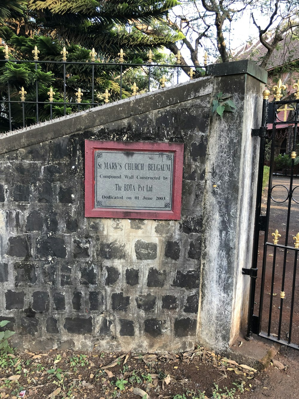 a sign on a stone wall near a fence