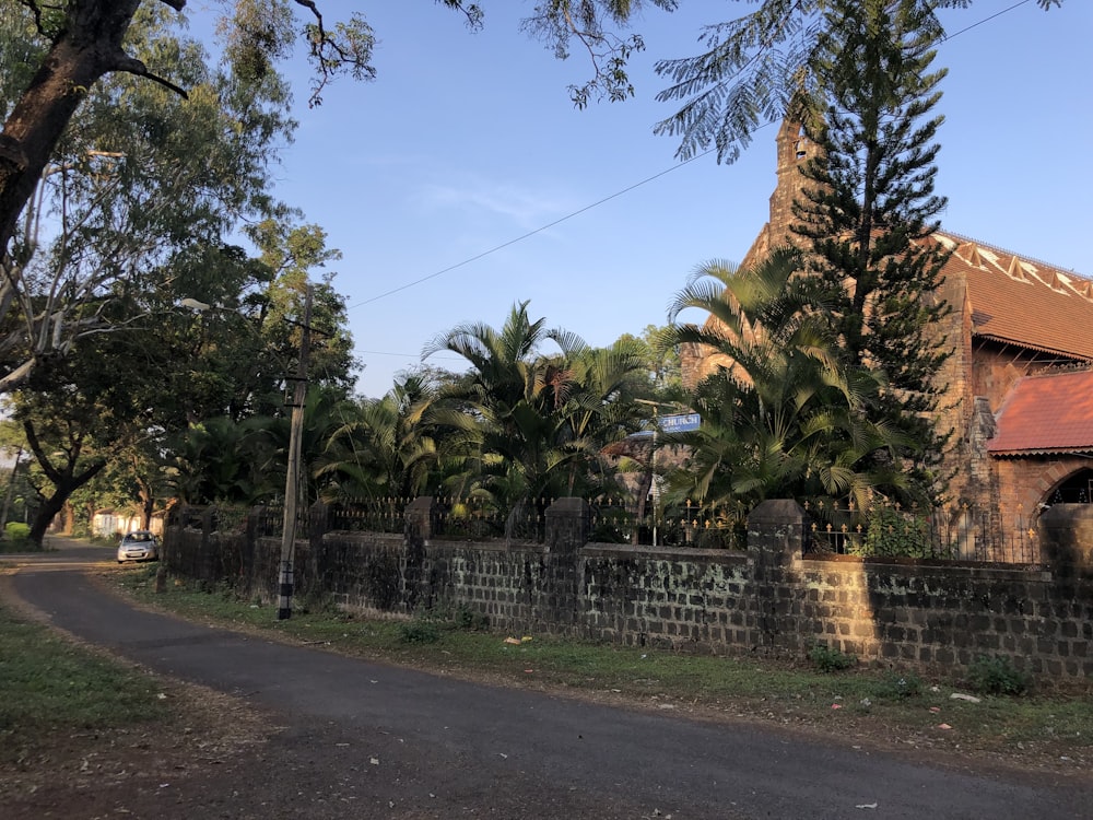 a brick building with a clock tower next to a tree lined road