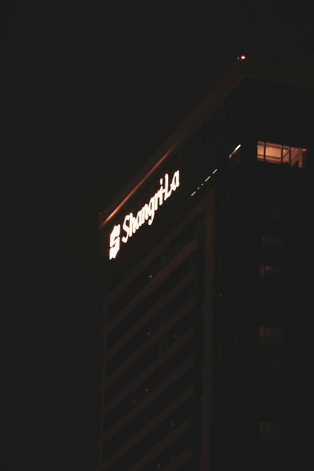 um edifício alto com uma placa iluminada em cima dele