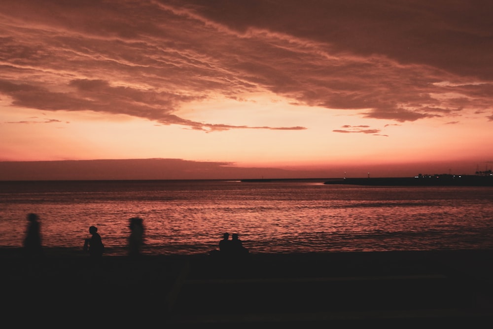 a group of people standing on top of a beach under a cloudy sky