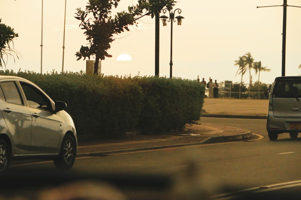 a car driving down a street next to a bush