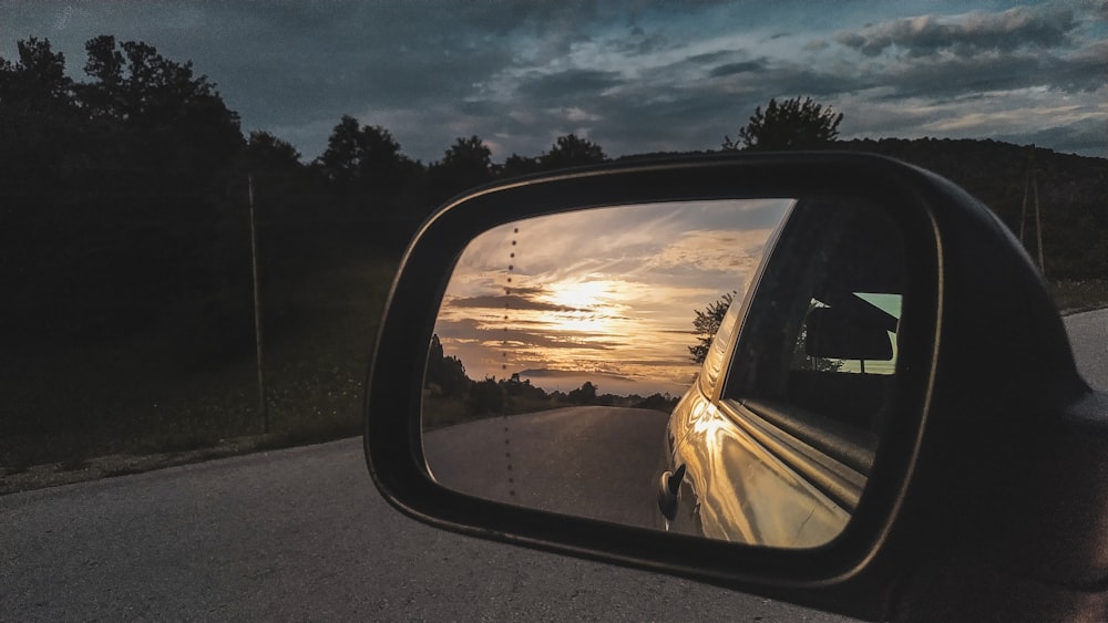 a rear view mirror on a car reflecting a sunset