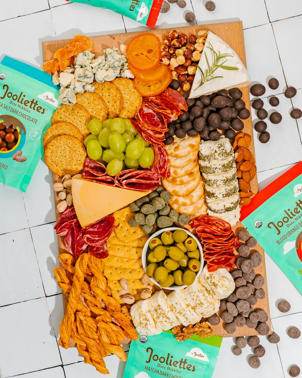 a platter of cheese, crackers, olives, crackers, nuts