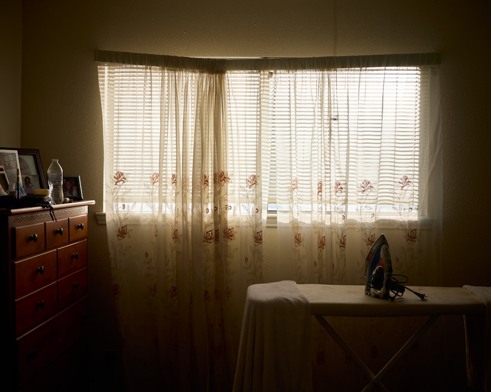 a room with a table and a window with sheer curtains