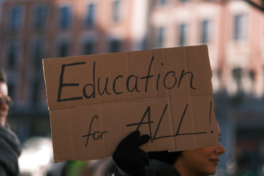 a person holding a sign that says education for all