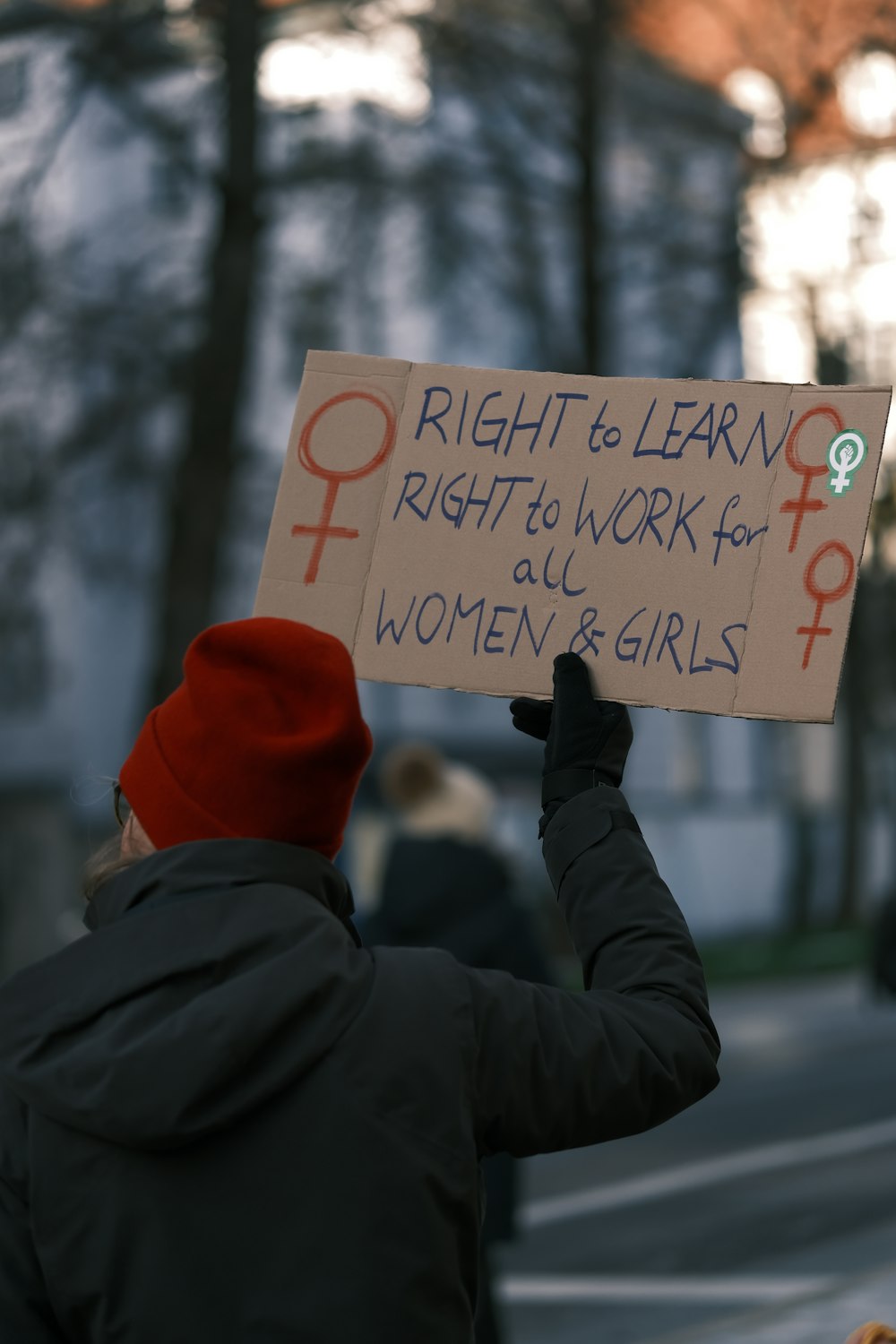 eine Person, die ein Schild hält, auf dem das Recht auf Lernen steht, das Recht auf Arbeit für alle Frauen und