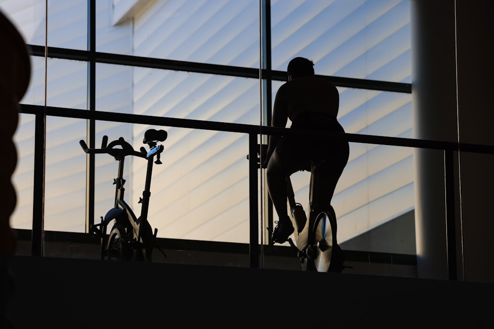 a man riding a bike next to a tall window