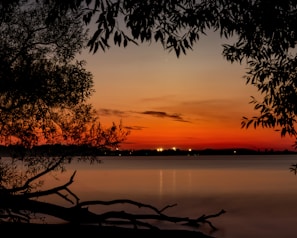 A scenic view of a sunset over a calm lake with reflections