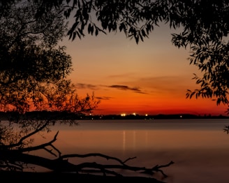 A scenic view of a sunset over a calm lake with reflections