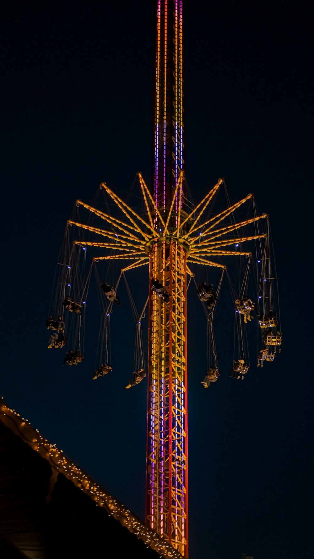 a ferris wheel lit up at night with a sky background