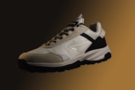 a pair of white and black sneakers on a brown background