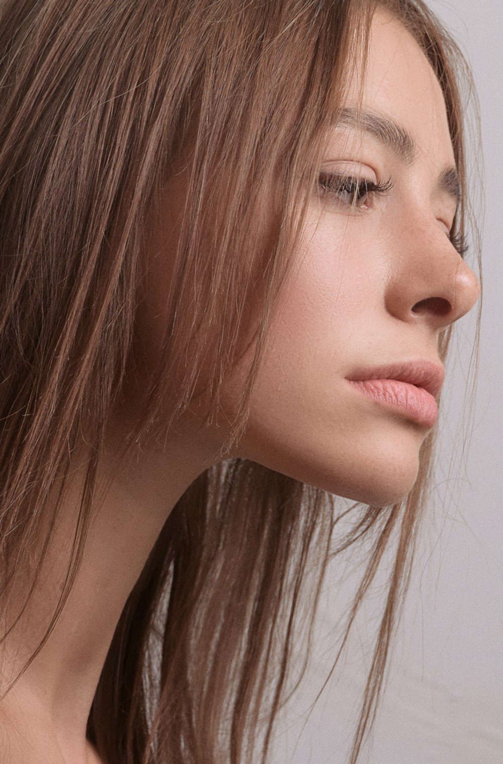 a close up of a woman's face with her hair blowing in the wind