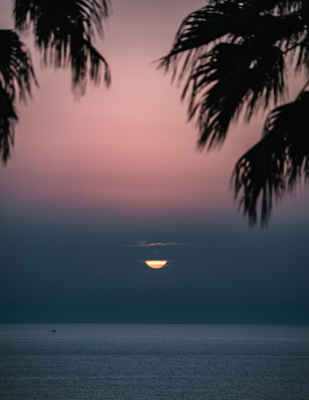 the sun is setting over the ocean as seen from a beach